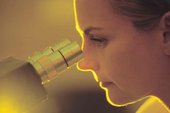 a woman looking through a microscope