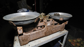 An old rusted double-pan balance is shown with a weighing stone on one pan.