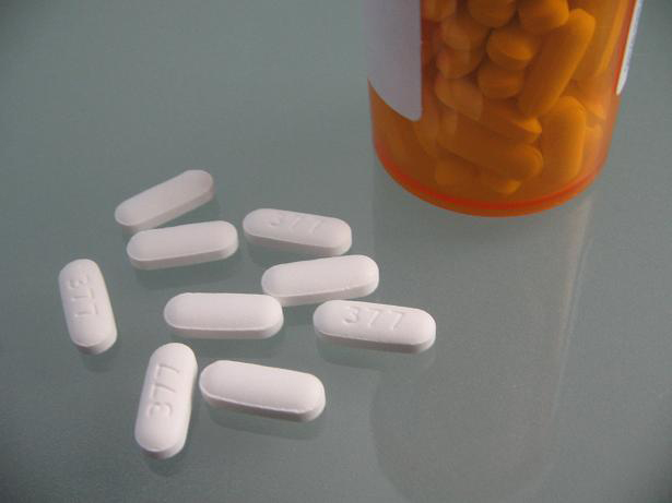 White pills next to a pill bottle are shown here.