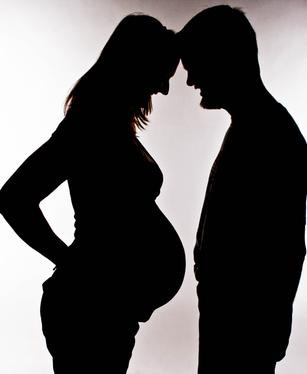A pregnant woman and a man in silhouette.