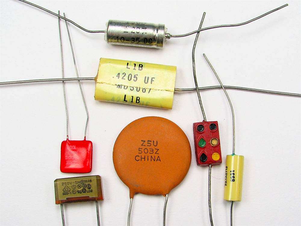 There are various types of capacitors with varying shapes and color. Some are cylindrical in shape, some circular in shape, some rectangular in shape, with two strands of wire coming out of each.