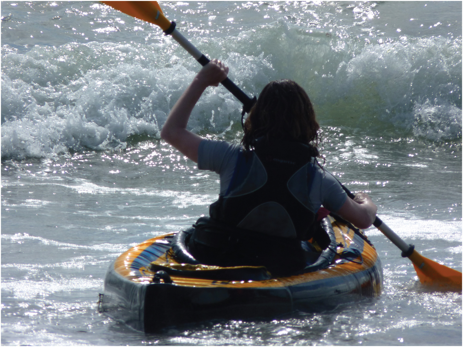 This picture shows a girl kayaking in the ocean.