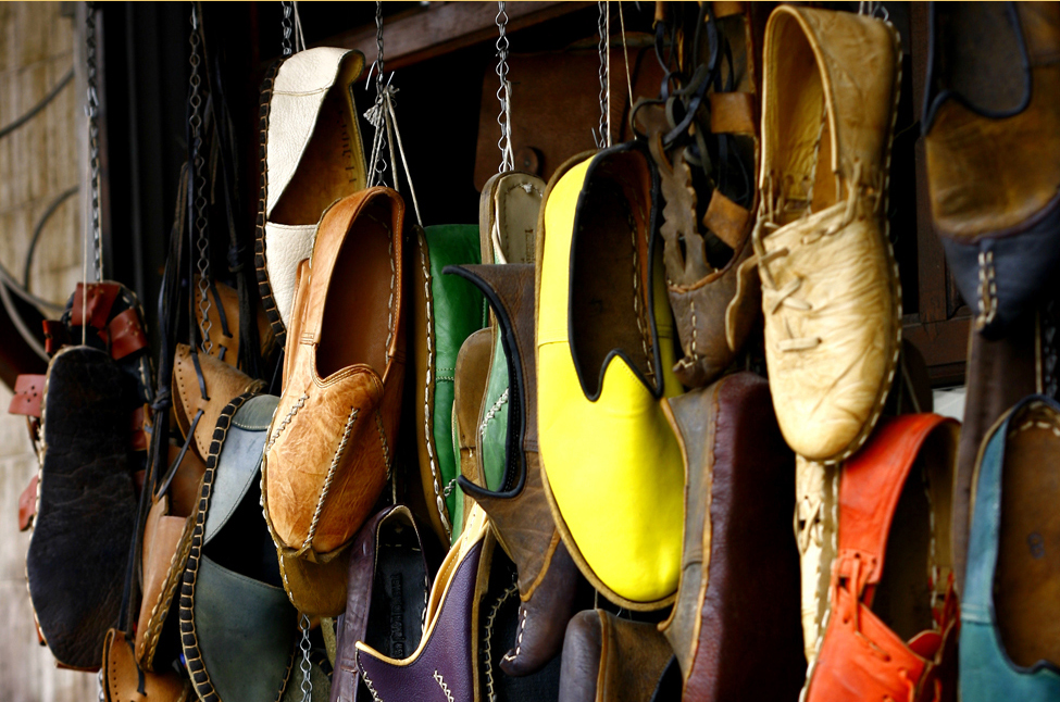 This photo shows many different pairs of shoes in various colors. The shoes appear to be hanging from a wall by cords.