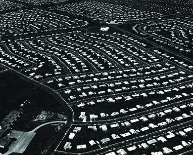 An aerial photograph of Levittown, Pennsylvania shows acres of land with standardized homes in neat rows.