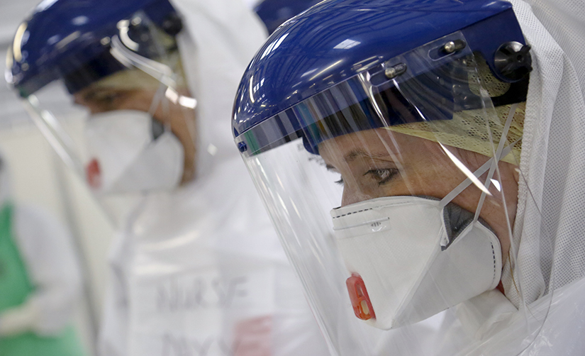 This photo depicts medical workers with a face mask and gloves training for safety so they can enter infection zones.