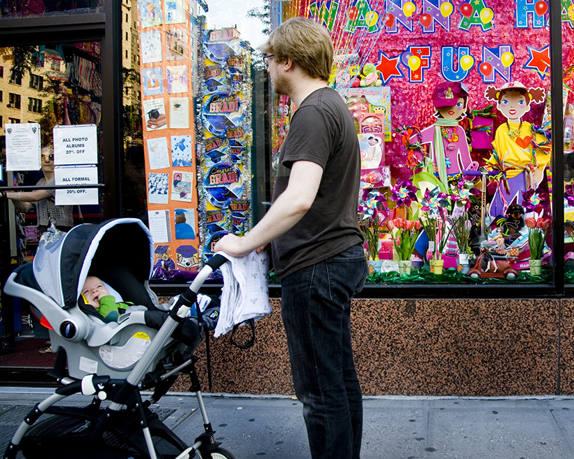 A photo of a man pushing a baby in a stroller down the street