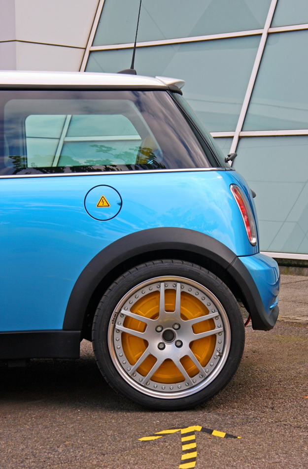 The figure shows the left side of a hatchback car’s back area, showing the font of its rear wheel. There is an arrow on road pointing its head toward this wheel.