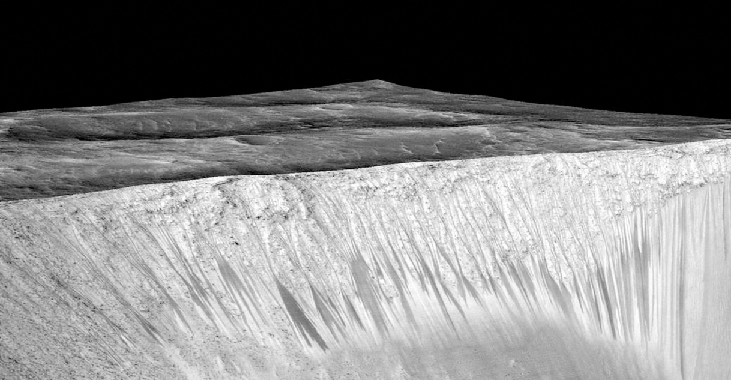 The wall of Garni crater. The wall of the crater comprises the lower half of this image. The dark streaks that run nearly vertically on the lower half of the crater wall are clearly visible.