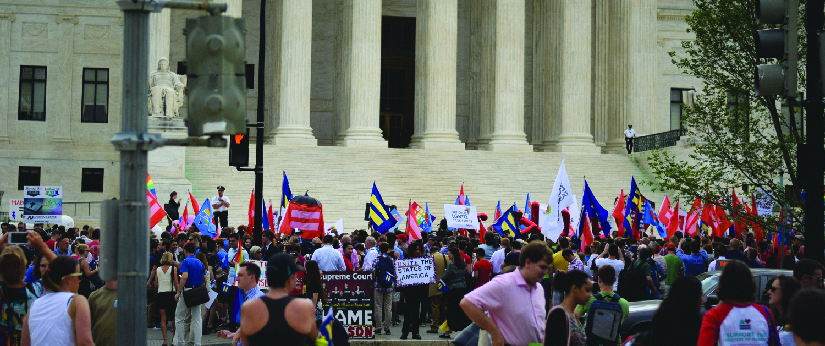 An image of a group of people standing in front of a building. Some people are holding signs.