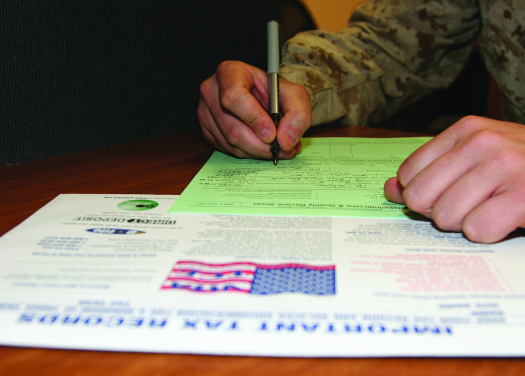 An image of a person’s hand, holding a pen over a form.