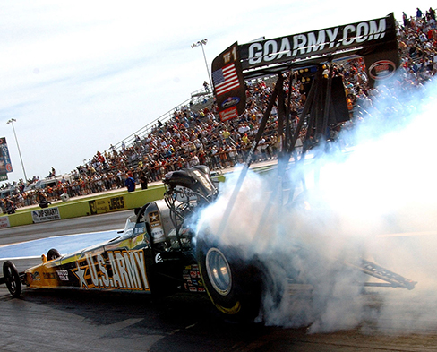 Picture shows a race car with smoke coming off of its back tires.