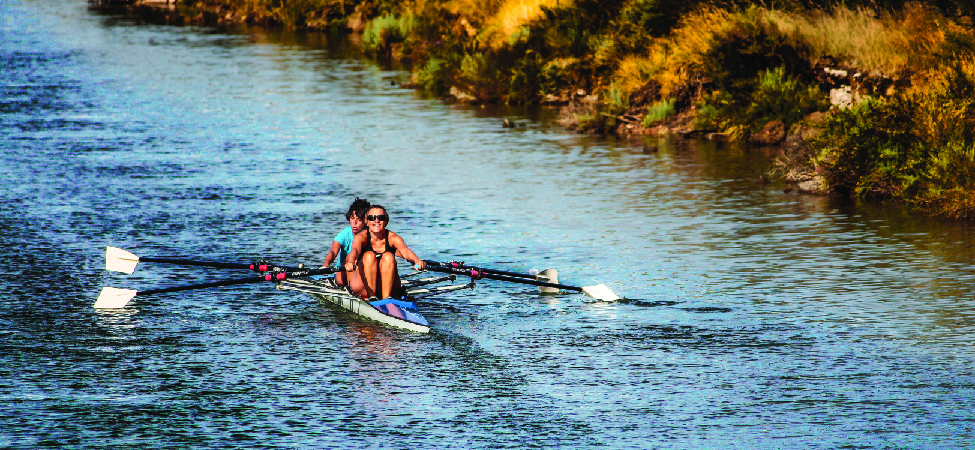 This is a photo of two people rowing a boat in a canal.